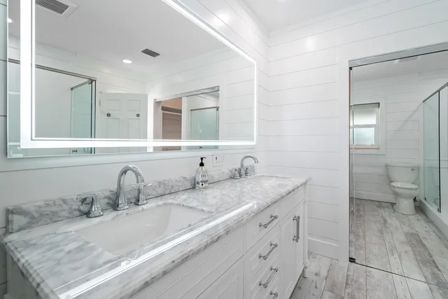 a bathroom with a granite countertop double vanity sink a mirror and a toilet