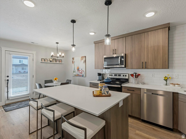 3047 Old Emigrant Road, Unit C Syracuse, UT 84075 - Photo 7 of 20 Kitchen with stainless steel appliances, tasteful backsplash, a kitchen breakfast bar, a center island, and light wood finished floors
