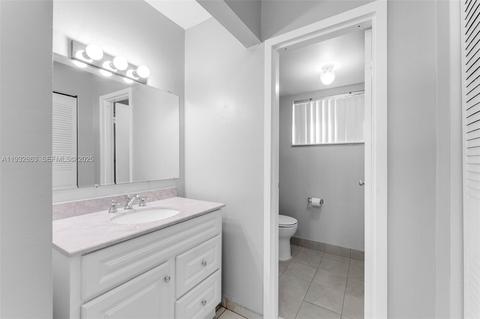 14180 Southwest 84th Street, Unit 508G Miami, FL 33183 - Photo 19 of 32 a bathroom with a sink a toilet and a mirror