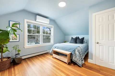 a bedroom with a bed dresser and a large window
