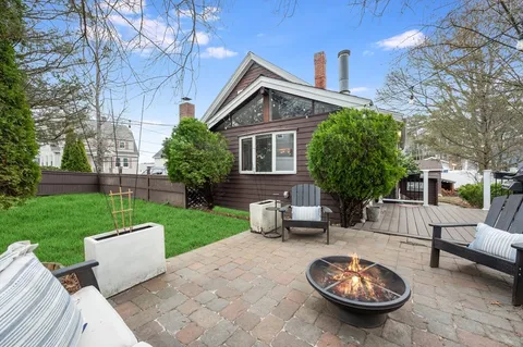 a view of a patio with table and chairs and a barbeque with wooden floor and fence