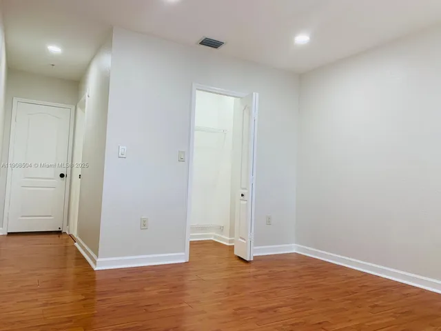 a view of an empty room with wooden floor and closet