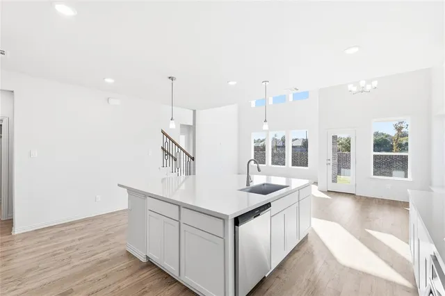 a large white kitchen with kitchen island a sink a center island stainless steel appliances and a couch