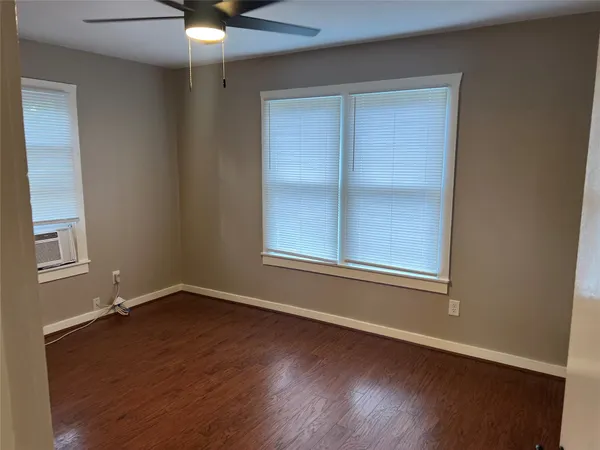 an empty room with wooden floor closet and windows