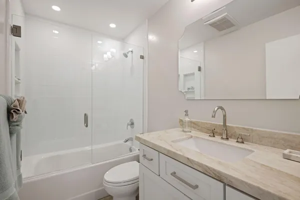 a bathroom with a granite countertop sink a toilet and shower