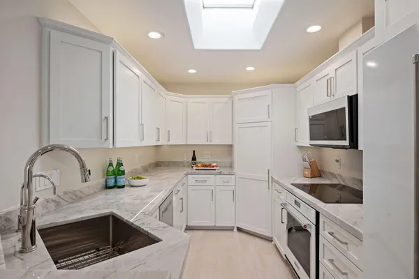 a kitchen with granite countertop a sink and white cabinets