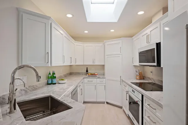 a kitchen with granite countertop a sink and white cabinets