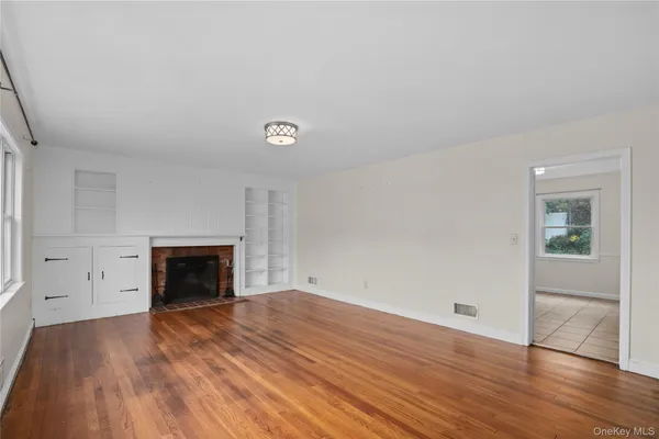 an empty room with wooden floor and fireplace
