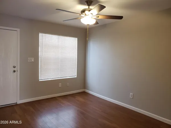 an empty room with wooden floor fan and windows