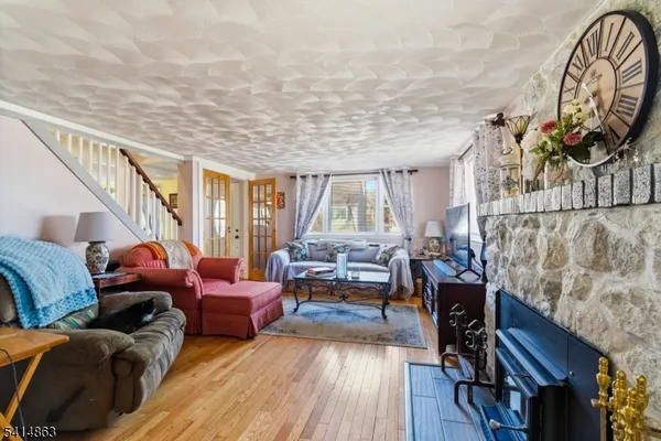 a living room with furniture a fireplace and a large mirror with wooden floor