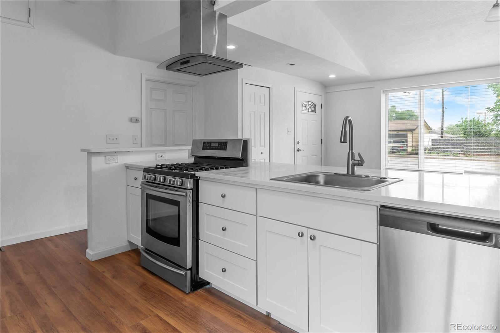 7010 West 44th Avenue Wheat Ridge, CO 80033 - Photo 9 of 31 a kitchen with granite countertop a stove a sink and a refrigerator