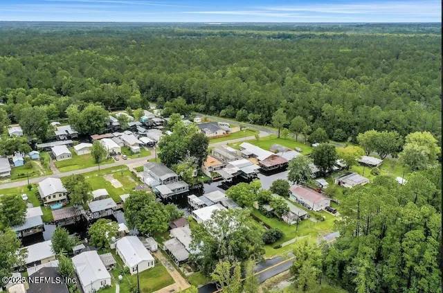 an aerial view of residential house with outdoor space and trees all around