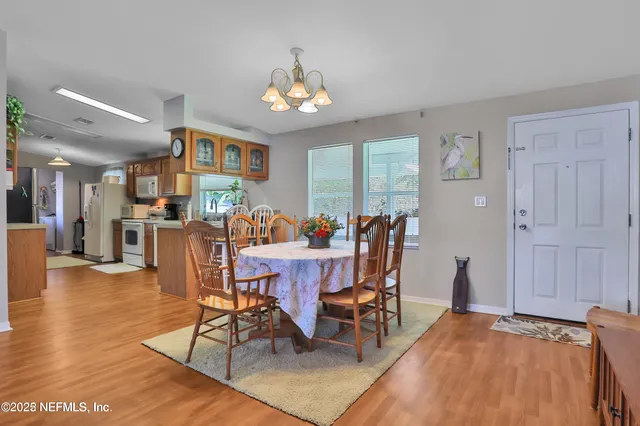 a dining room with wooden floor a chandelier a glass table and chairs