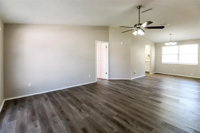 an empty room with wooden floor window and ceiling fan