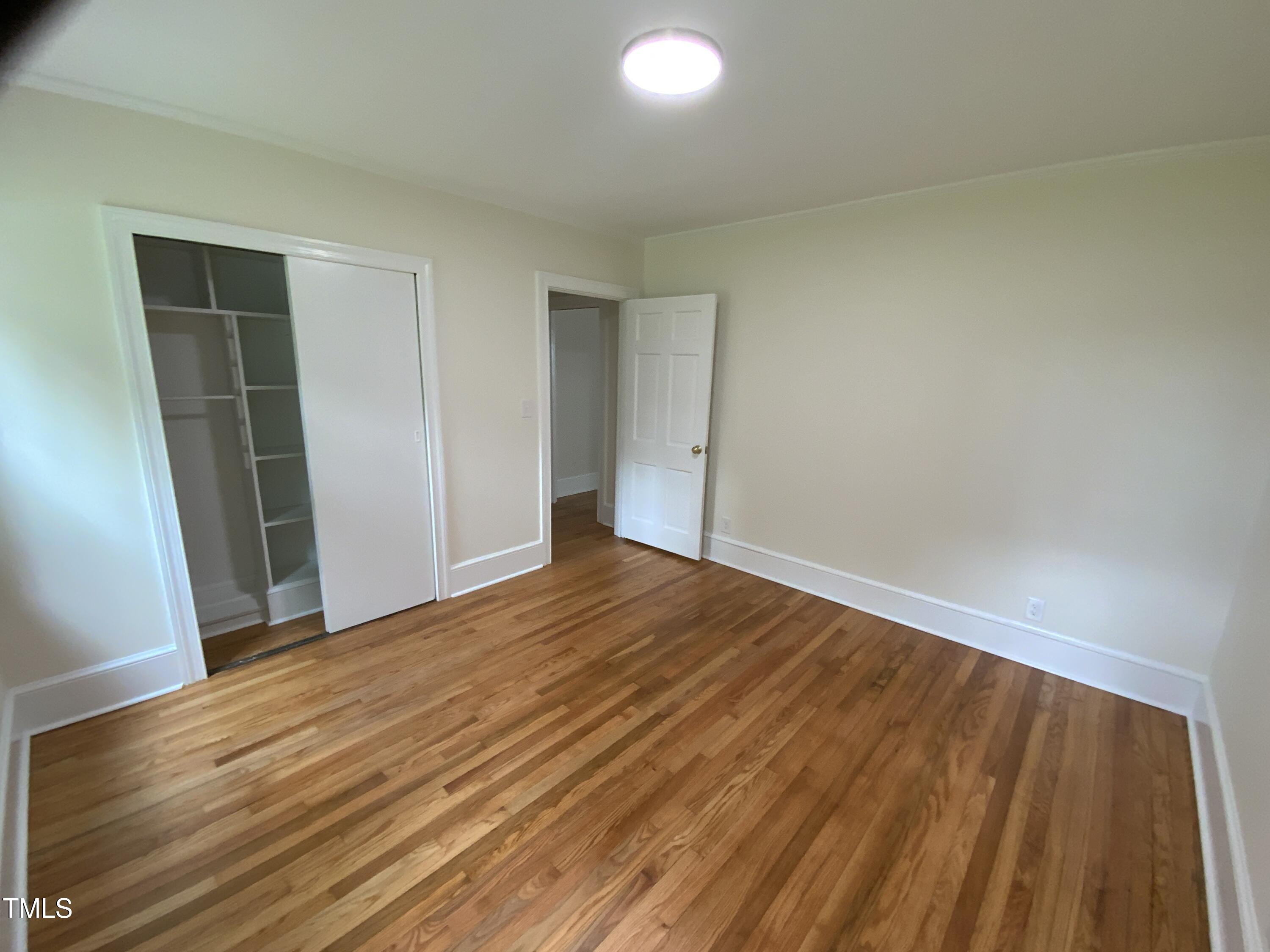 1101 West Divine Street Dunn, NC 28334 - Photo 17 of 36 a view of an empty room with wooden floor and a window