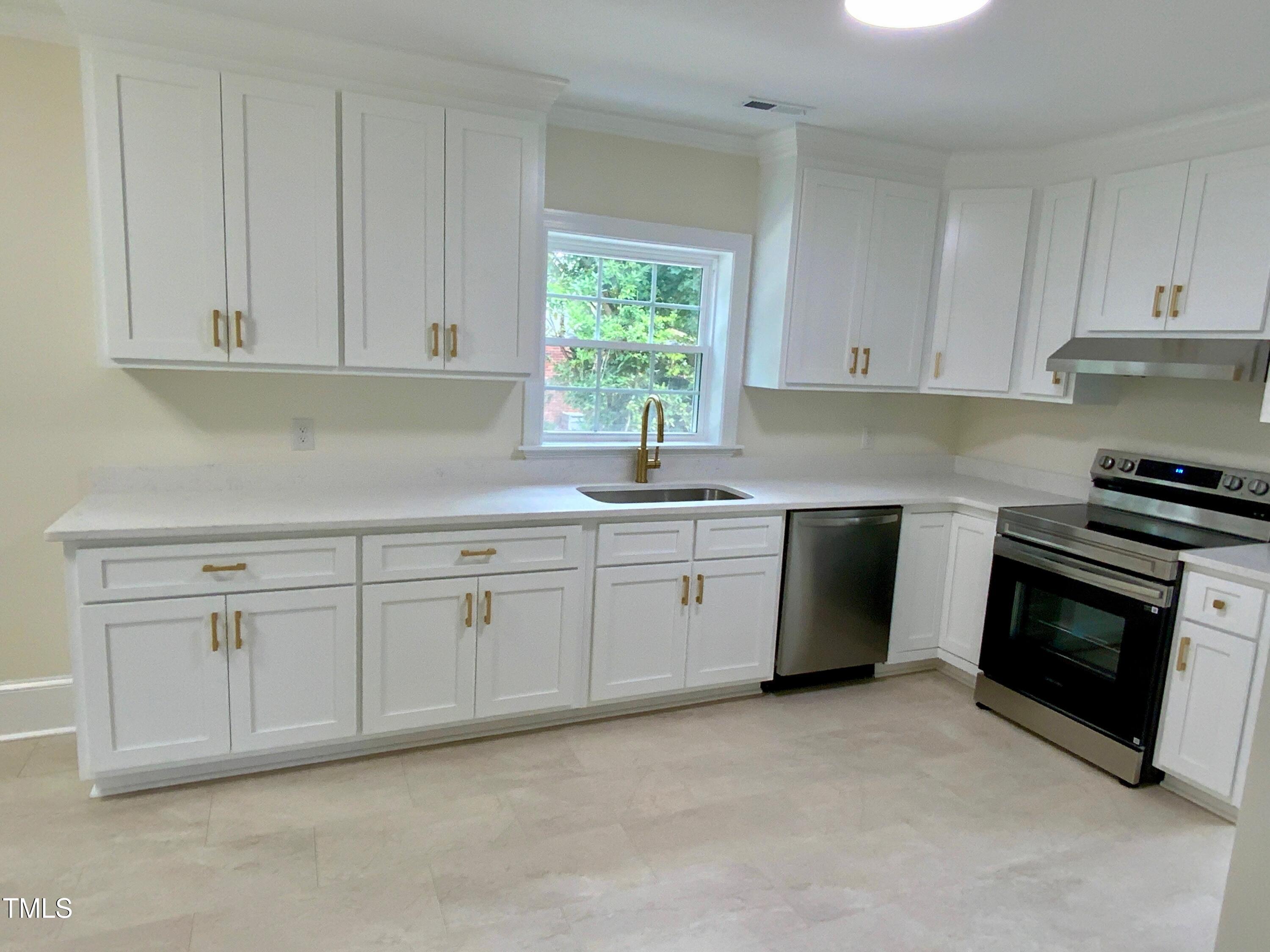 1101 West Divine Street Dunn, NC 28334 - Photo 4 of 36 a kitchen with white cabinets appliances a sink and a window