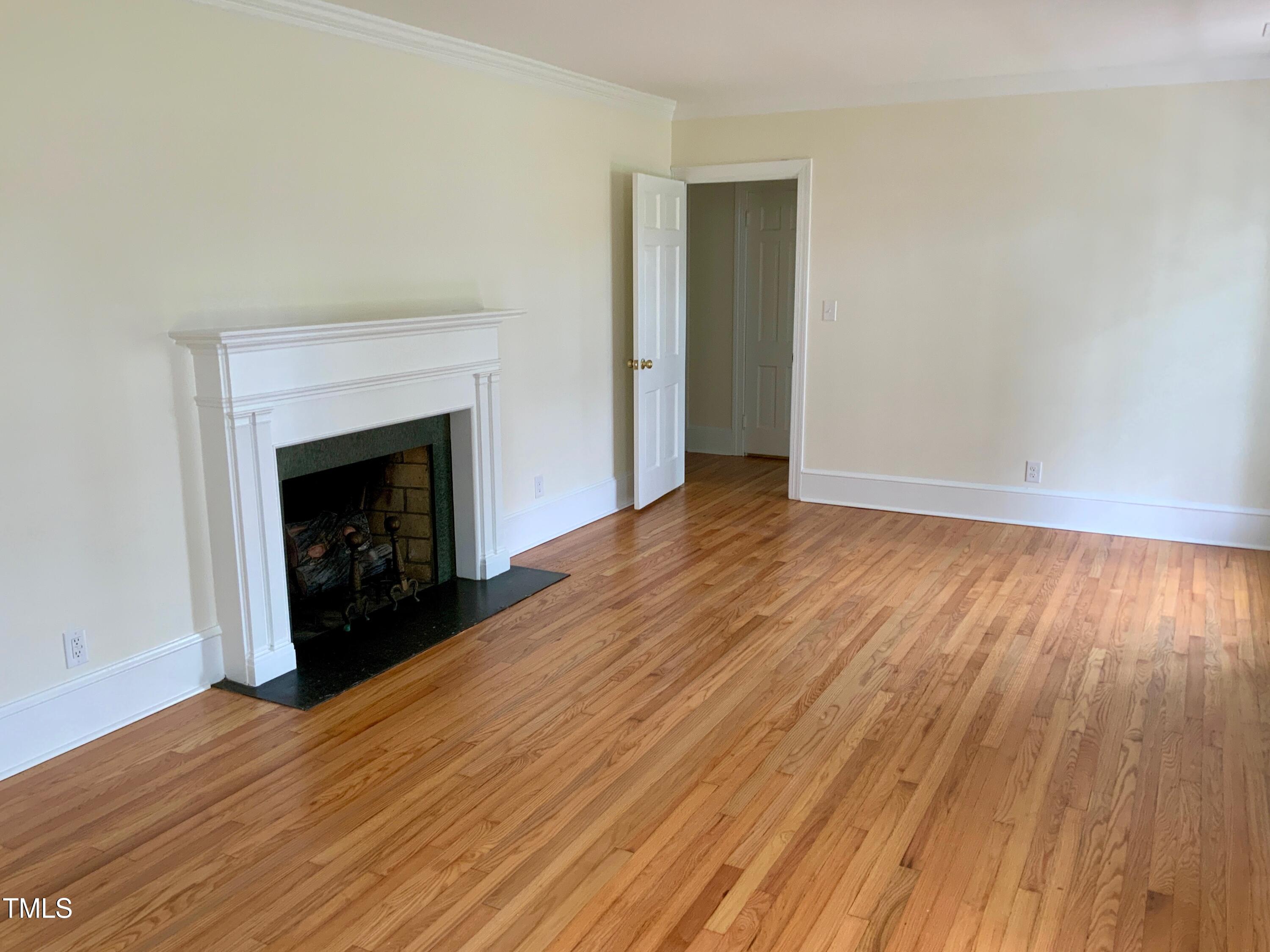 1101 West Divine Street Dunn, NC 28334 - Photo 7 of 36 a view of an empty room with wooden floor fireplace and a window