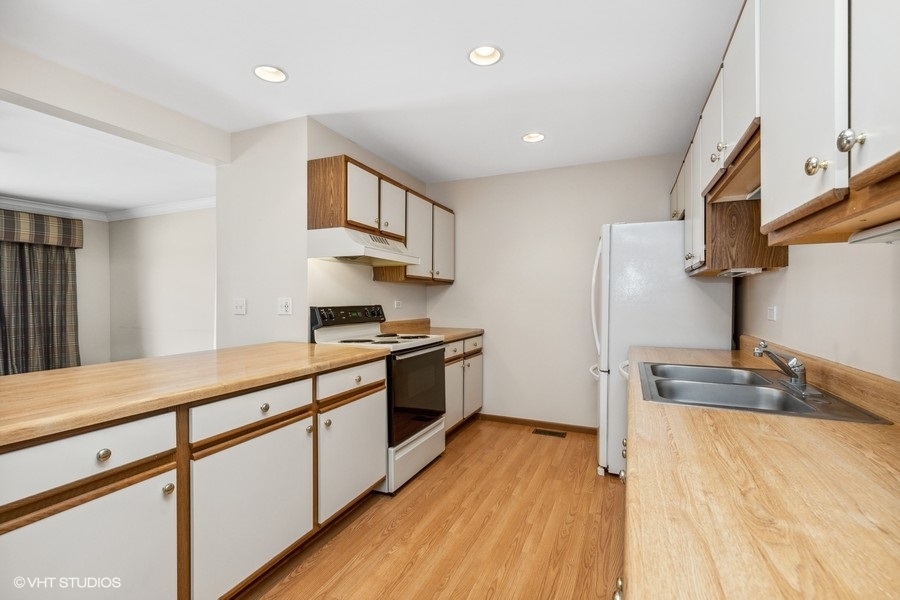 935 Golf Course Road, Unit 4 Crystal Lake, IL 60014 - Photo 7 of 17 a large kitchen with stainless steel appliances granite countertop a lot of counter space and wooden floor