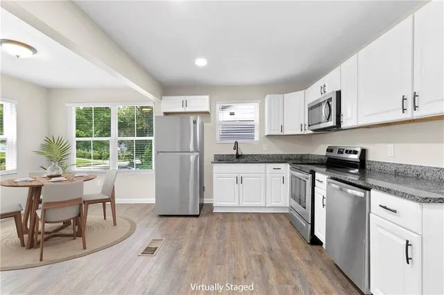 a kitchen with a refrigerator a white cabinets and wooden floor