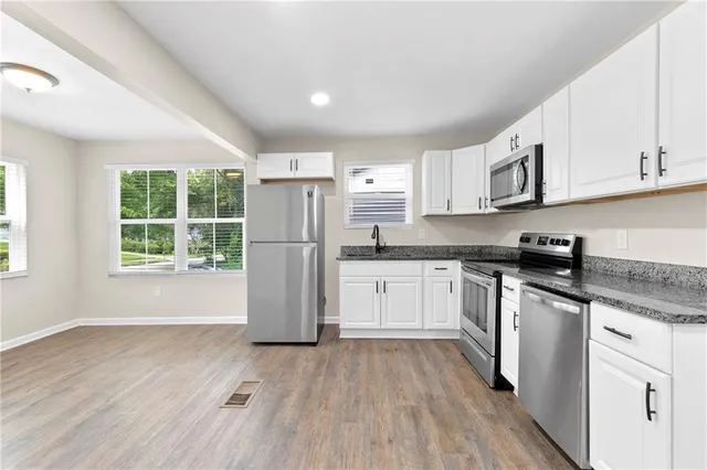 a kitchen with a refrigerator a sink dishwasher a stove and white cabinets with wooden floor