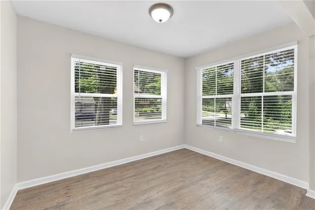 a view of an empty room with wooden floor and windows