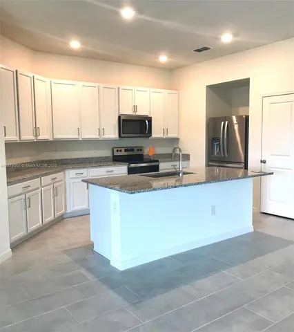a kitchen with kitchen island granite countertop a stove a sink and a microwave