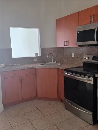 a kitchen with granite countertop a stove top oven microwave and cabinets