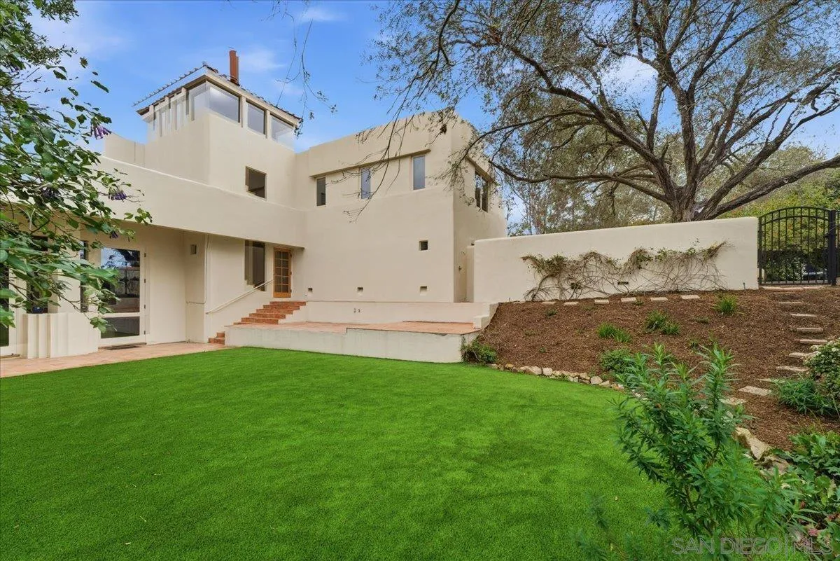 7030 Elfin Oaks Road Escondido, CA 92029 - Photo 3 of 36 a view of a white house next to a yard with big trees