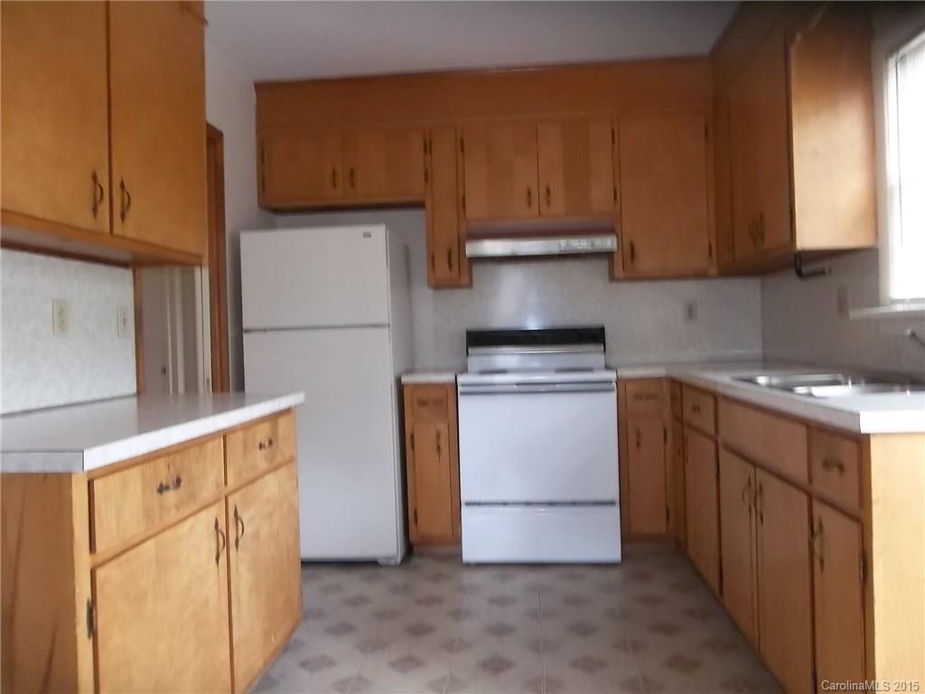 4227 Walker Road, Unit 4 Charlotte, NC 28211 - Photo 3 of 6 a kitchen with granite countertop wooden cabinets and white appliances