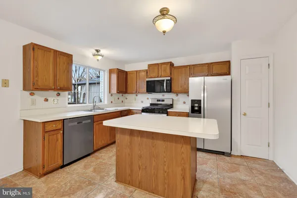 a kitchen with stainless steel appliances granite countertop a sink stove refrigerator and cabinets