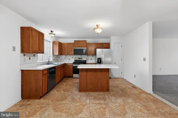 a large kitchen with stainless steel appliances kitchen island granite countertop a sink a stove a refrigerator a counter top space and cabinets