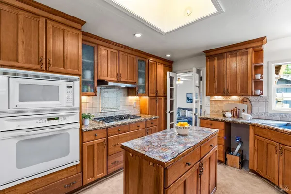 a kitchen with stainless steel appliances granite countertop a stove top oven a sink dishwasher and cabinets with wooden floor