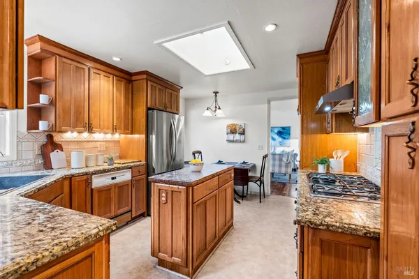 a kitchen with stainless steel appliances granite countertop a stove a sink dishwasher and a refrigerator