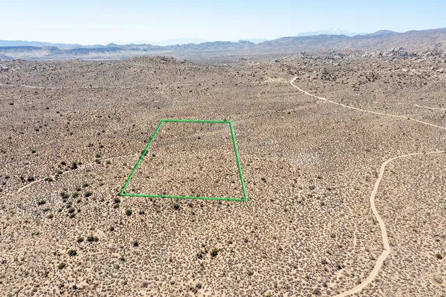 a view of a dry yard with mountains in the background