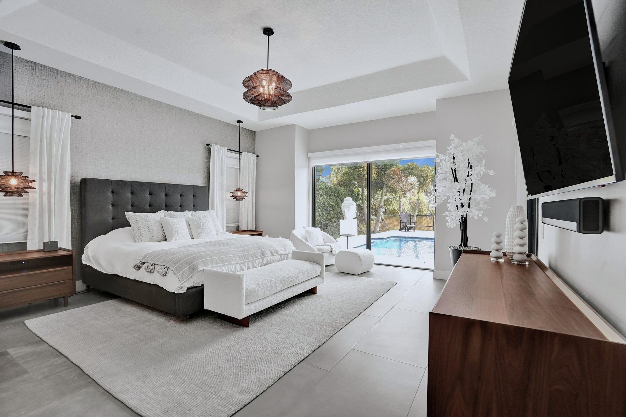 3222 Ridge Trace Davie, FL 33328 - Photo 30 of 77 a spacious bedroom with a bed a chandelier and large window