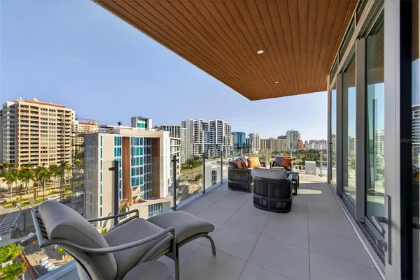a view of a terrace with chairs and a floor to ceiling window