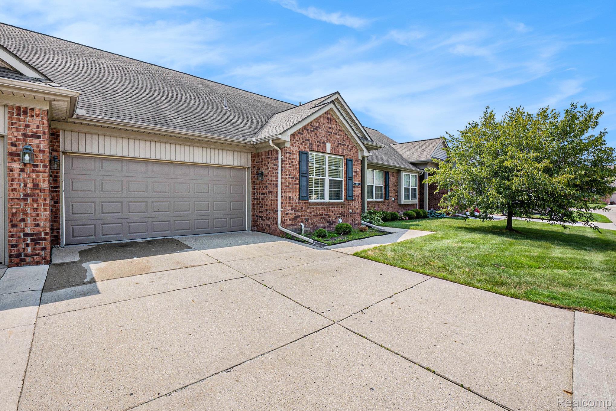 5477 Victory Circle Sterling Heights, MI 48310 - Photo 4 of 32 Brick facade residence featuring a two-car garage, concrete driveway, and well-maintained lawn