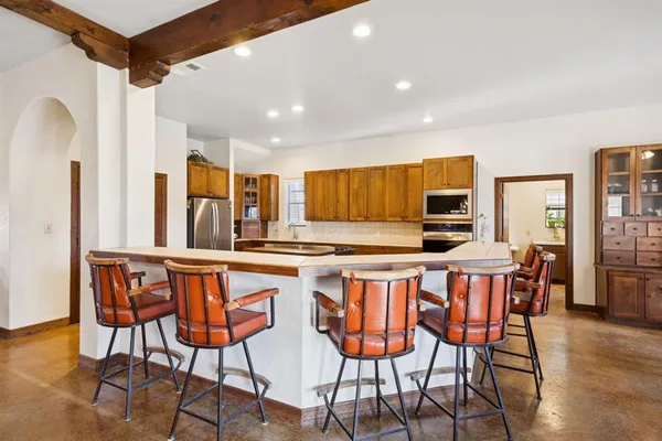 a kitchen with stainless steel appliances a table and chairs in it