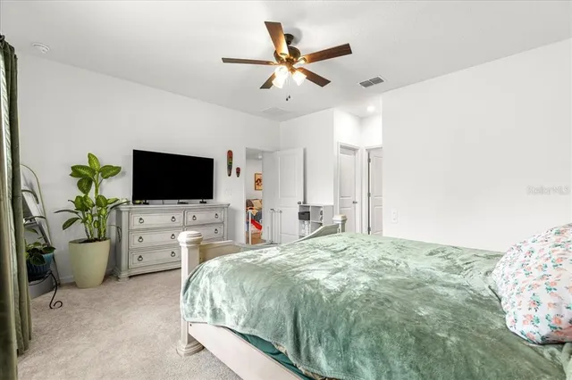 a spacious bedroom with a bed and a flat screen tv