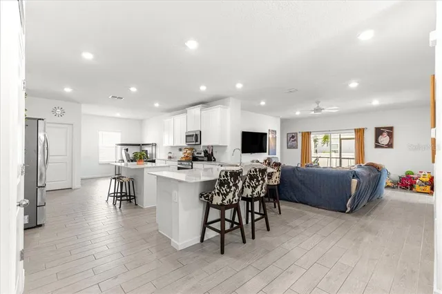 a view of kitchen with kitchen island stainless steel appliances refrigerator dining table and chairs