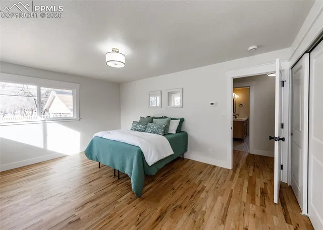 a spacious bedroom with a bed and wooden floor