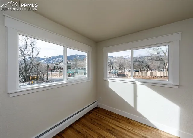 a view of an empty room with wooden floor and a window