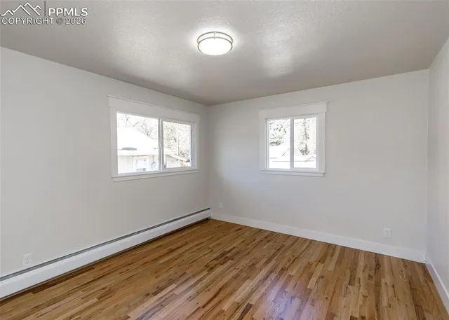 an empty room with wooden floor and windows