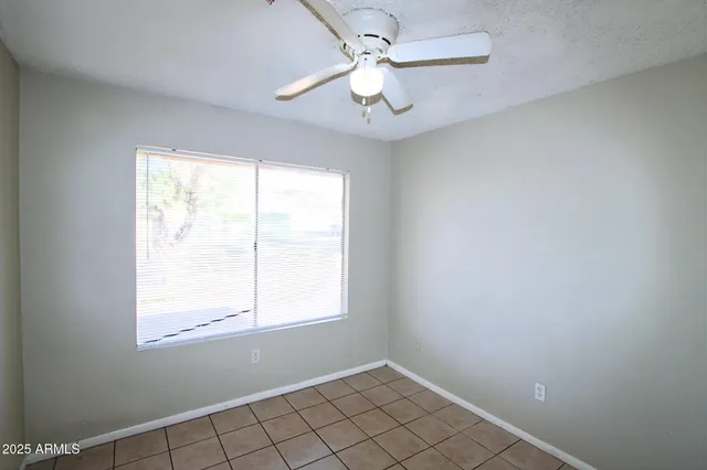 an empty room with windows and fan