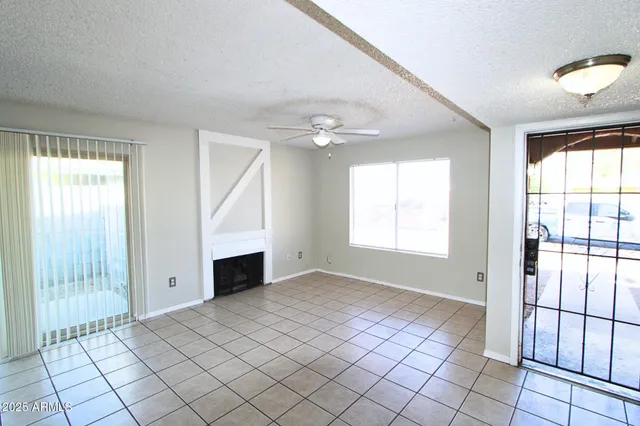 a view of an empty room with window and chandelier fan