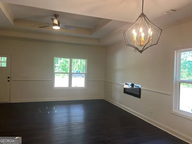 an empty room with wooden floor chandelier fan and windows