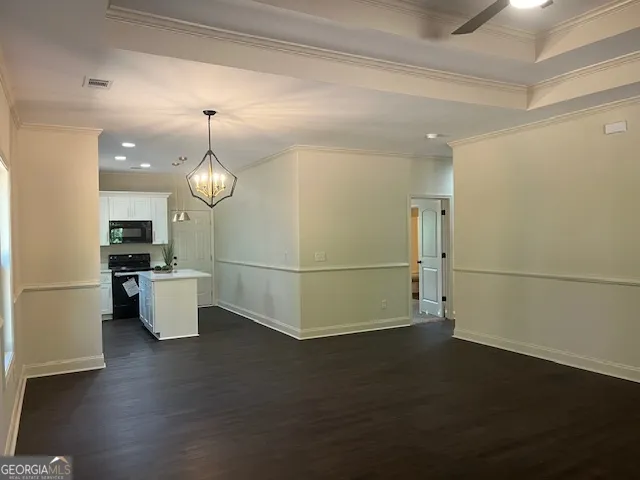 an empty room with wooden floor and kitchen view
