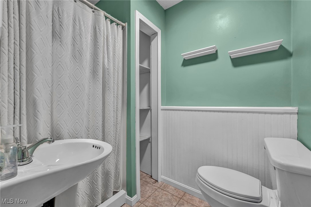 47655 Cooper Foster Park Road Amherst, OH 44001 - Photo 21 of 49 Full bath with a wainscoted wall, tile patterned floors, and curtained shower