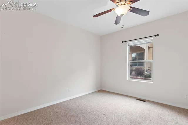an empty room with a window and a fan