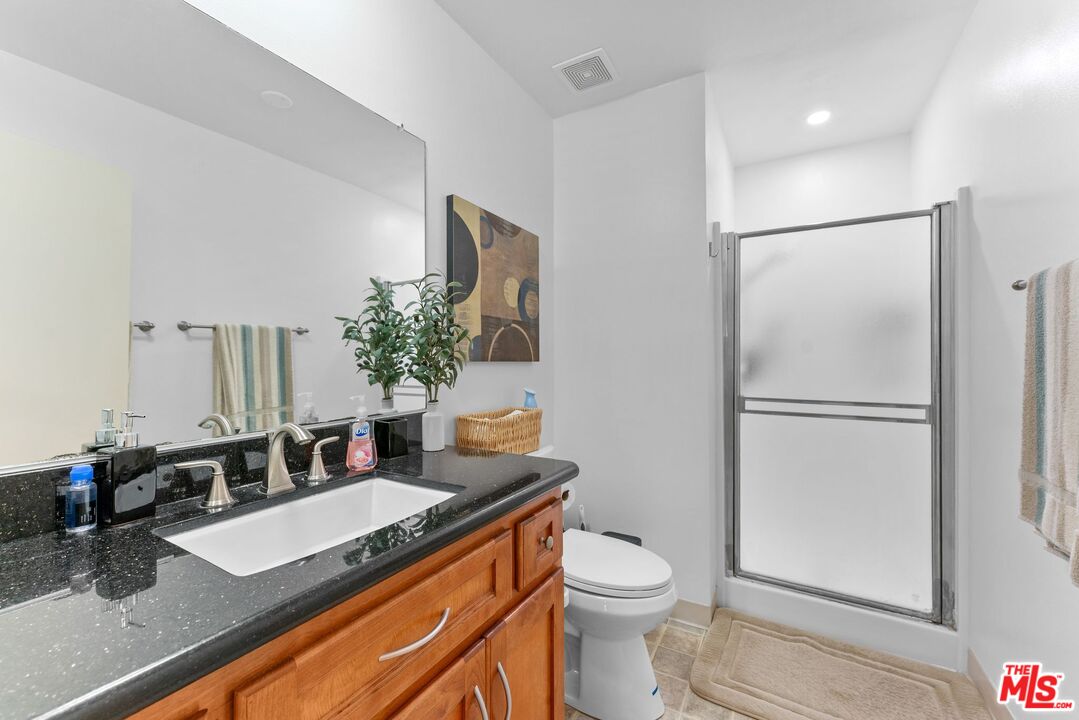 612 South Barrington Avenue, Unit 317 Los Angeles, CA 90049 - Photo 15 of 17 a bathroom with a granite countertop sink a toilet and a mirror